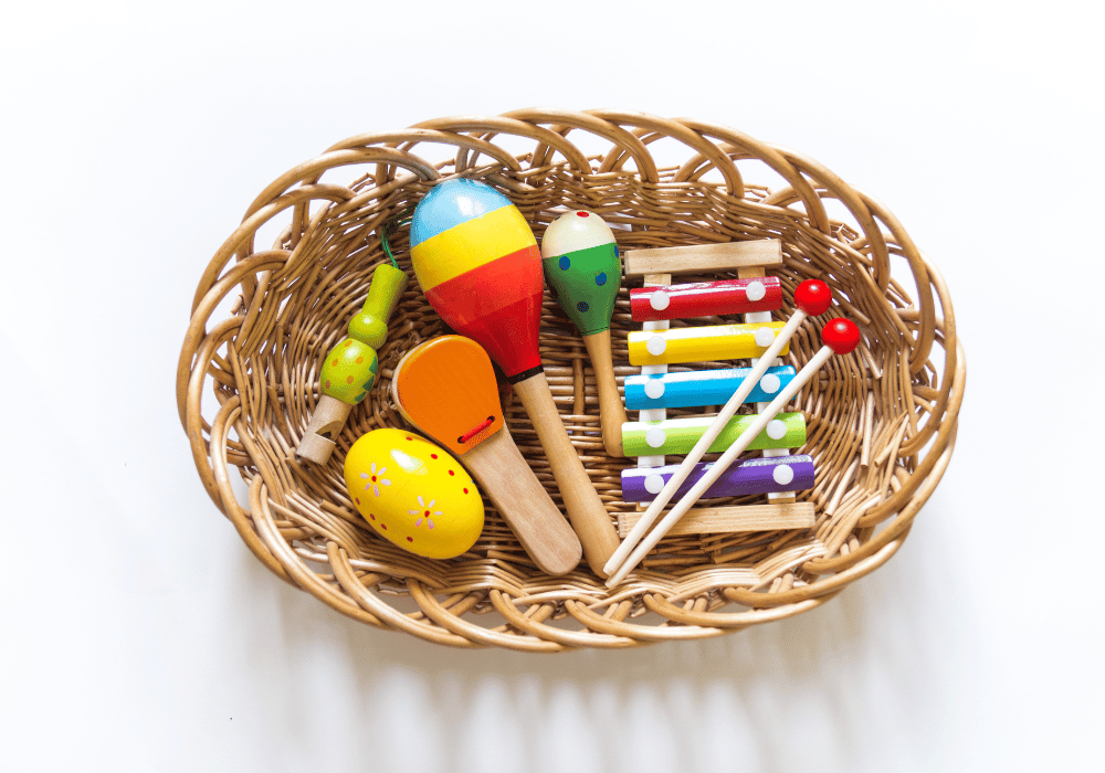 Плетена кошница с цветни дървени музикални инструменти за деца – маракаси и ксилофон.